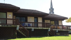 A building with a traditional architectural style, featuring a prominent tower and a balcony with a wooden railing.
