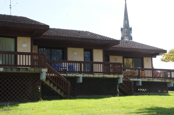 Un bâtiment de style architectural traditionnel, caractérisé par une tour imposante et un balcon doté d’une balustrade en bois.