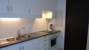 A kitchen with white cabinets, a double sink, a coffee maker, and an oven.