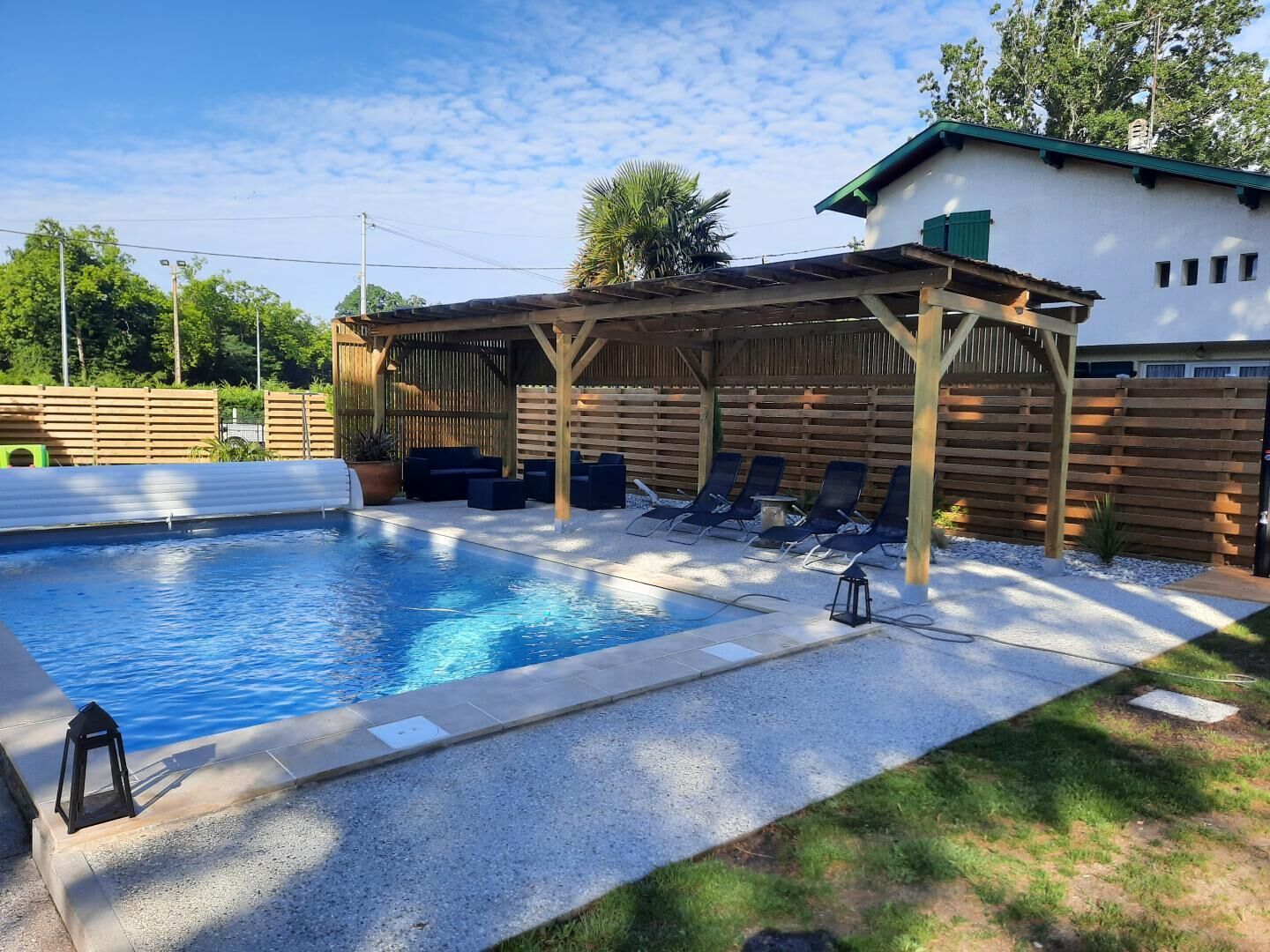 Una piscina con lettini e una zona relax ombreggiata.