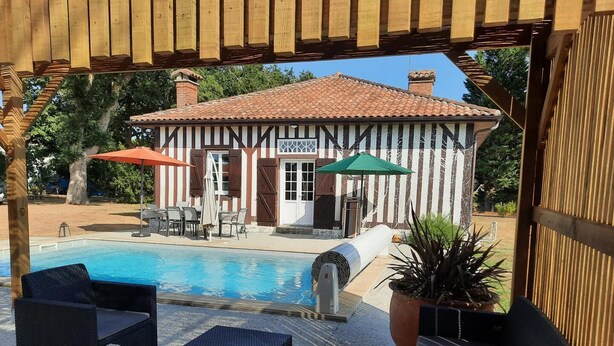 A poolside area with outdoor seating and a view of a building with a tiled roof.