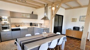 A modern kitchen with grey cabinets, a striped tablecloth, and white chairs.