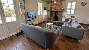A living room with a fireplace, grey sofas, a television, and a patterned rug.