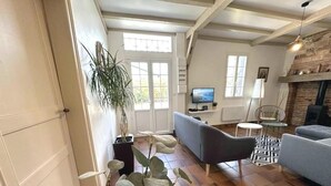 A living room with a sofa, a television, a fireplace, and a plant.