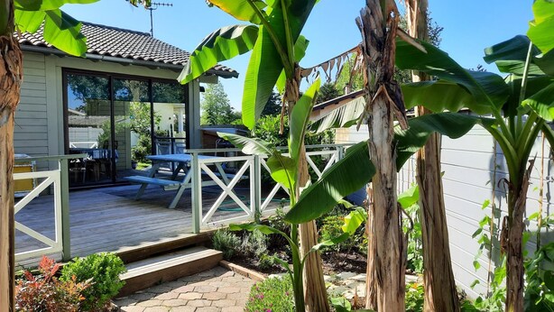 A wooden deck with a picnic table and chairs, surrounded by lush greenery and a white fence. - Chalet Simone - ST-VINCENT-DE-TYROSSE (ST-VINCENT-DE-TYROSSE)