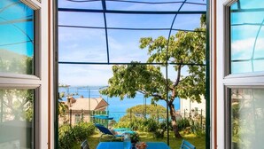 A view from a window with a table and chairs outside, a tree, and a building in the background. - Cherry Tree House-Affitti Brevi Italia (Recco)