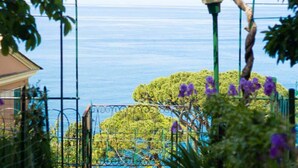 A coastal view with a metal fence, a lamp post, and purple flowers in the foreground. - Cherry Tree House-Affitti Brevi Italia (Recco)