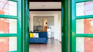A room with a bed, a sofa, and a kitchen area visible through an open door. - Cherry Tree House-Affitti Brevi Italia (Recco)
