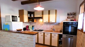 Una cocina compacta con pared de ladrillo, estufa a gas, lavamanos y horno de acero inoxidable.