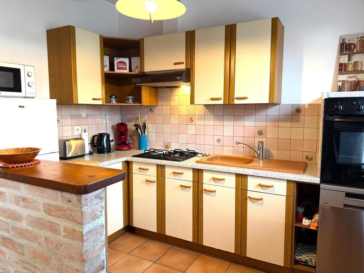 A compact kitchen with wooden cabinets, a gas stove, a sink, and a built-in oven.