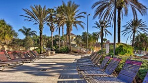 A poolside area with lounge chairs and palm trees.