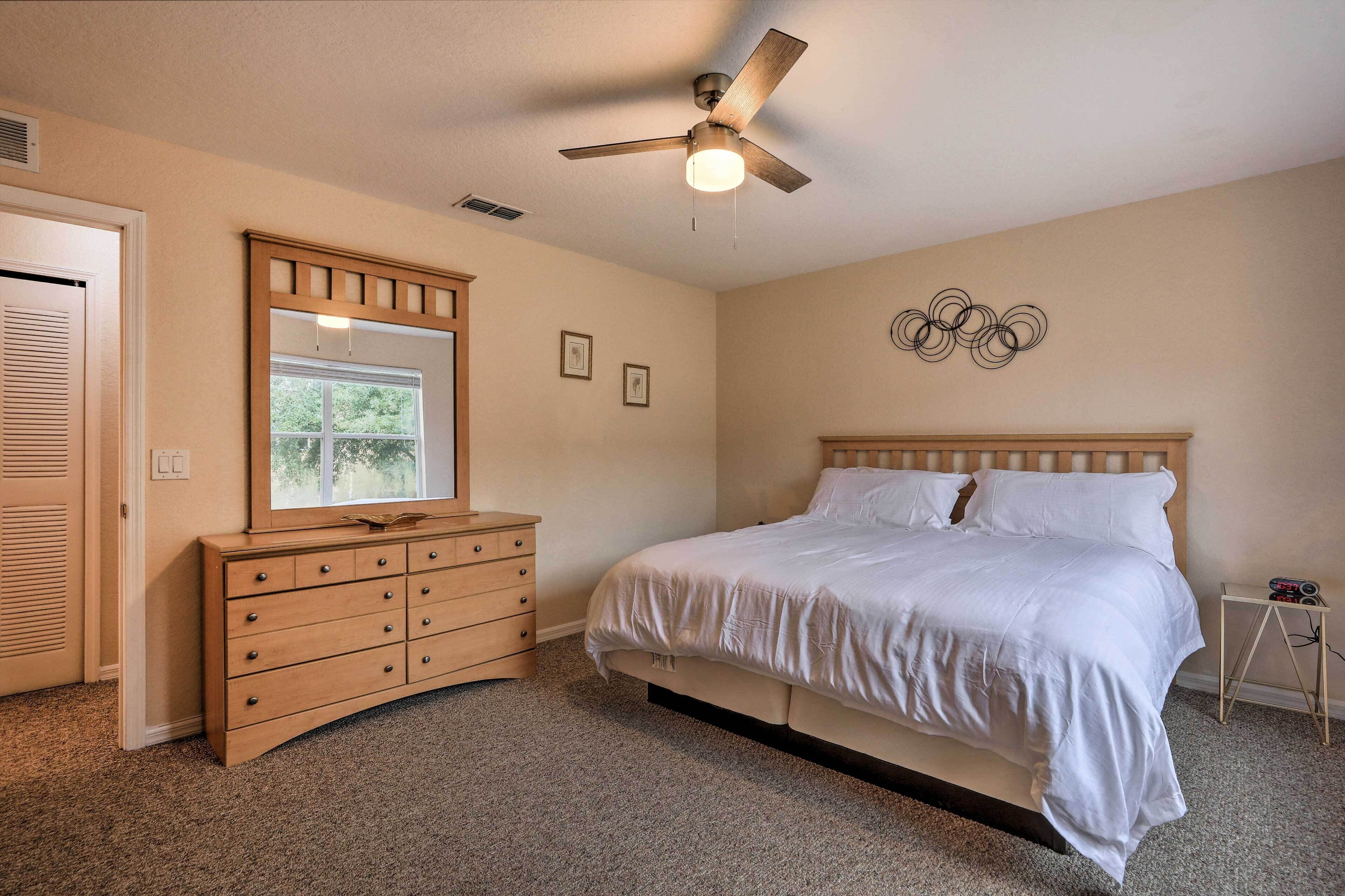 Une chambre à coucher avec un lit, une commode, un ventilateur de plafond et une fenêtre.