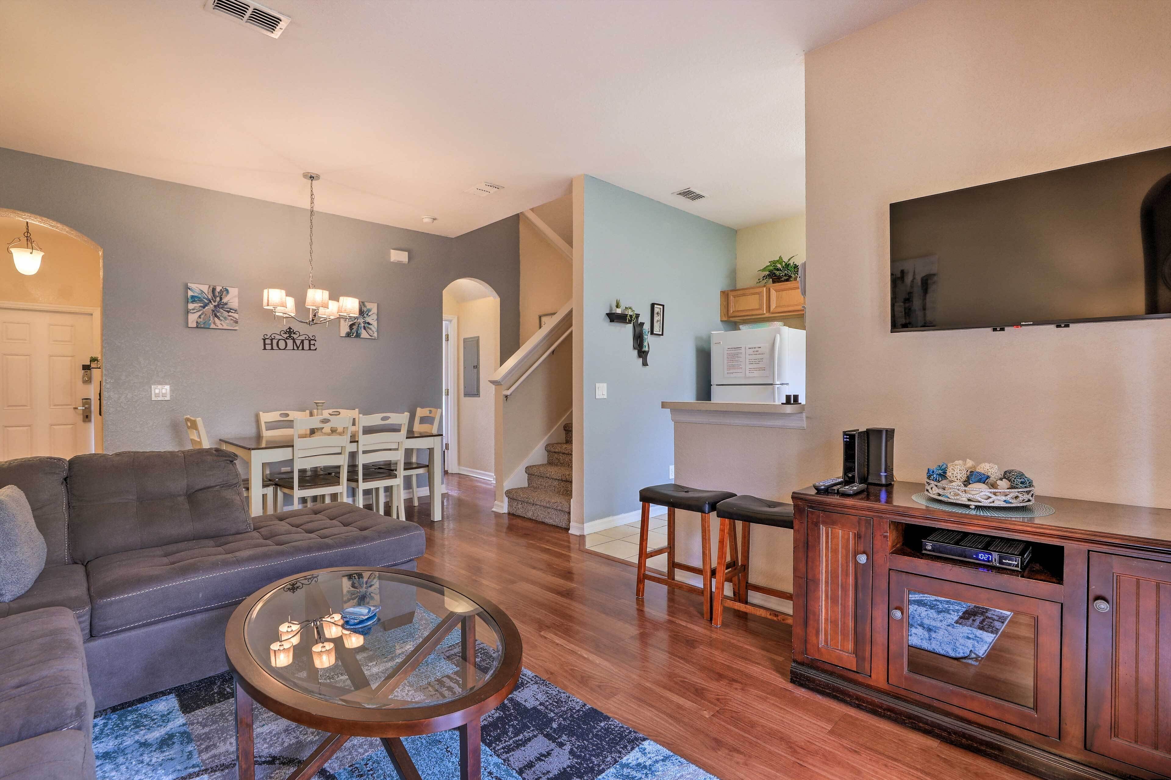A living room with a grey sofa, a glass coffee table, and a wooden cabinet with a flat-screen TV.