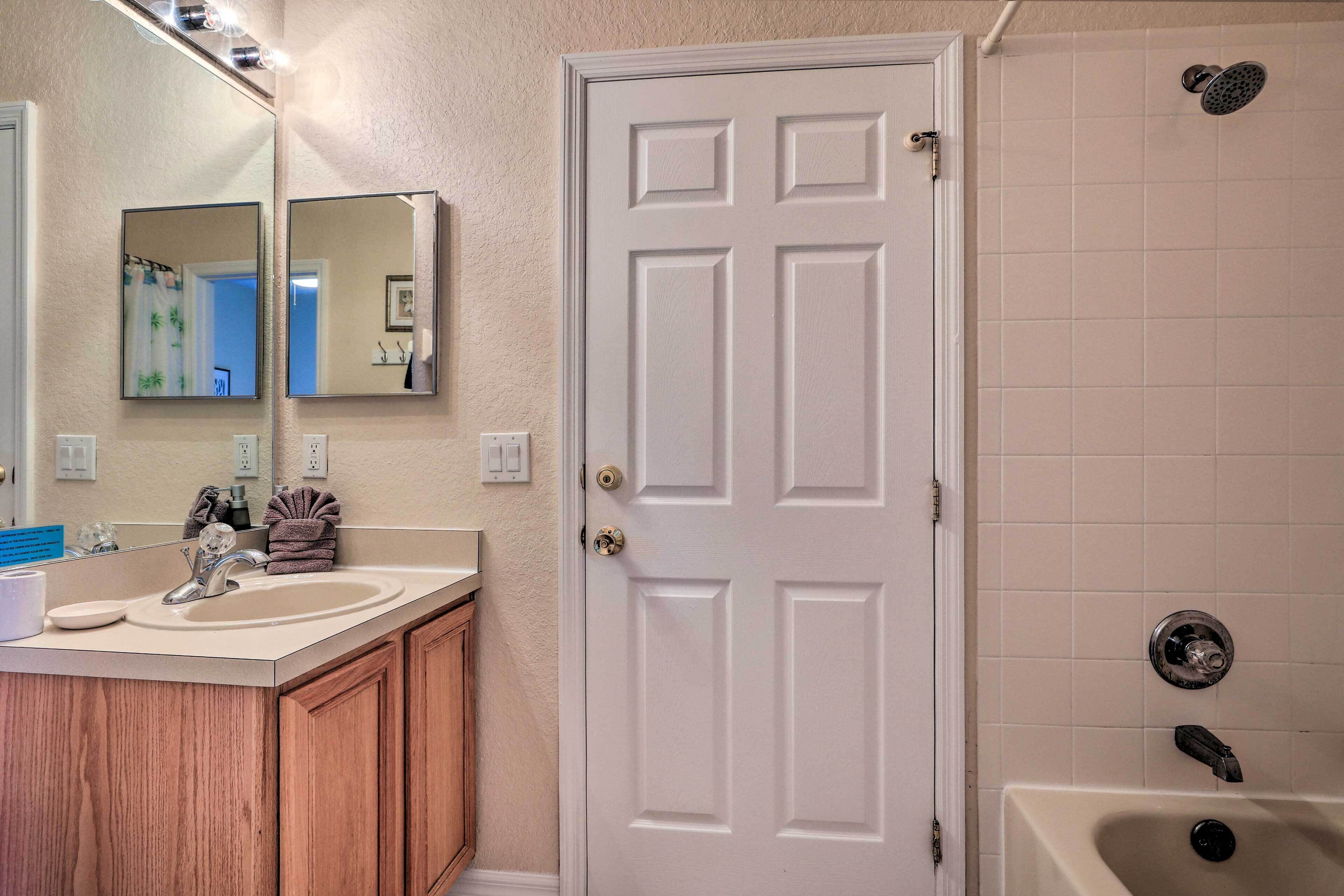 Une salle de bain avec une porte blanche, un lavabo avec un miroir et un espace douche.