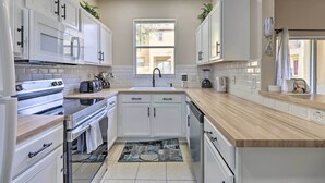 A modern kitchen with white cabinets, a built-in microwave, a toaster, and a coffee maker.