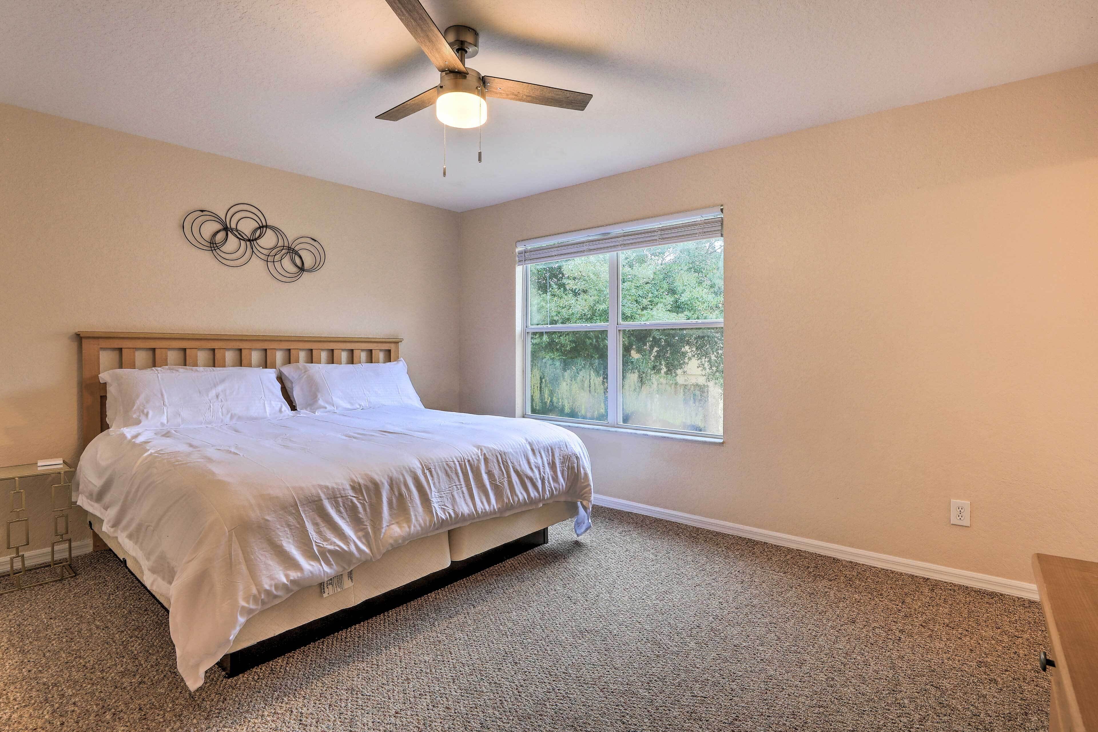 Une chambre à coucher avec un lit, un ventilateur de plafond, une fenêtre et un élément décoratif mural.