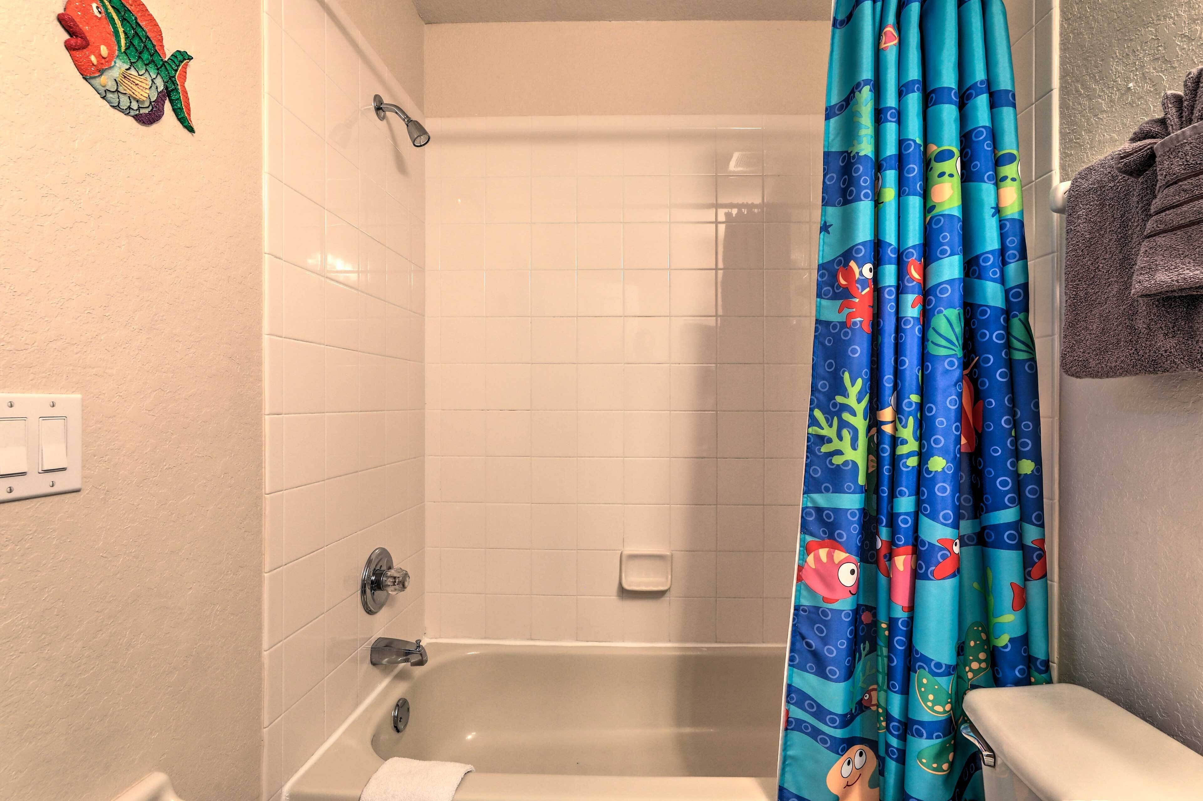 A bathroom with a shower curtain featuring sea creatures, a bathtub, and a toilet.
