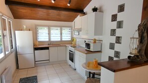 A compact kitchen with white cabinets, a microwave, a sink, and a wooden ceiling. - Gîte de la Mousque - Castets (CASTETS)
