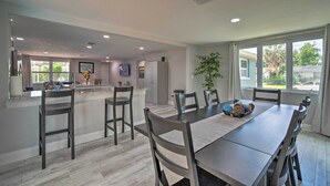A modern kitchen with a central island, dining table with chairs, and large windows. - Relaxing Port Richey Getaway w/ Lanai & Pool! (Port Richey)