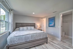 A bedroom with a bed, a nightstand, a lamp, a framed picture on the wall, and a closet. - Relaxing Port Richey Getaway w/ Lanai & Pool! (Port Richey)