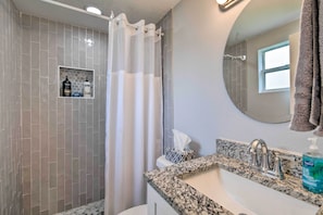 A bathroom with a shower, a sink with a granite countertop, a mirror, and a window. - Relaxing Port Richey Getaway w/ Lanai & Pool! (Port Richey)