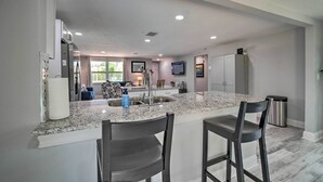 A modern kitchen with granite countertops, stainless steel appliances, and a central island with bar stools. - Relaxing Port Richey Getaway w/ Lanai & Pool! (Port Richey)