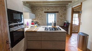 A compact kitchen with a central island, built-in oven, and a stone wall.