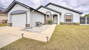 A two-story house with a garage, a stone archway, and a front porch with a bench. - Kissimmee Retreat w/ Private Basketball Court! (Kissimmee)