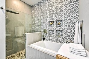 A modern bathroom with a glass-enclosed shower, a freestanding bathtub, and patterned tiles. - 'chic on the Beach' Luxe Anna Maria Island Retreat (Holmes Beach)