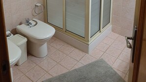 Une salle de bain comprenant des toilettes, un espace douche et un lavabo.