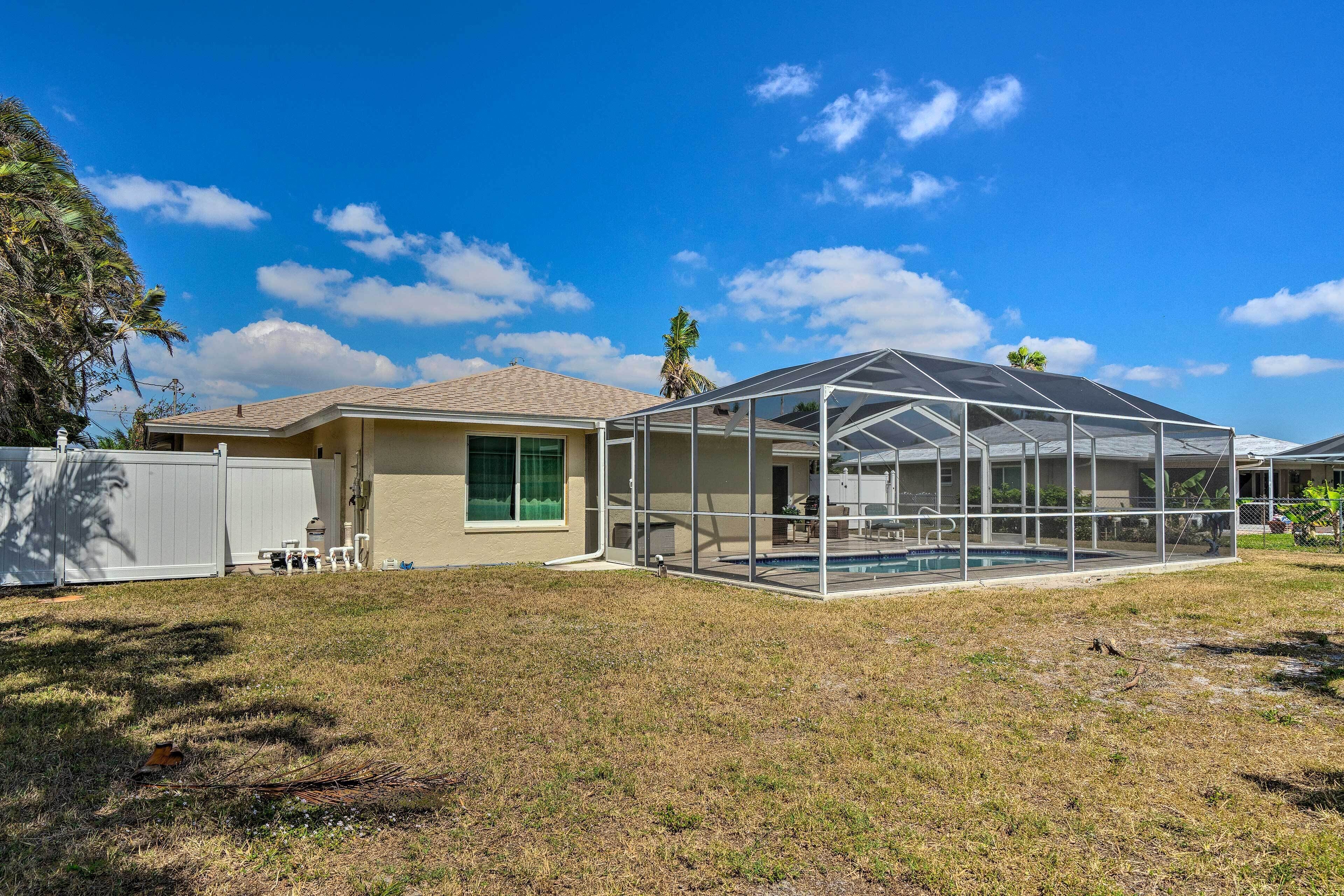 A house with a glass-enclosed patio, a swimming pool, and a fenced yard.