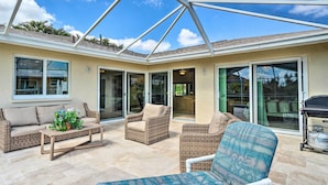 A covered patio area with wicker furniture, a coffee table, and a grill. - 6 Mi to Dtwn Cape Coral: Home w/ Spacious Lanai! (Cape Coral)