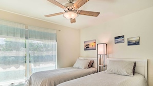 A bedroom with two beds, a ceiling fan, and artwork on the wall. - 6 Mi to Dtwn Cape Coral: Home w/ Spacious Lanai! (Cape Coral)