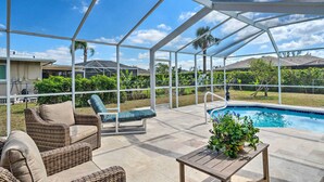 An outdoor patio with a pool, wicker furniture, and a covered area. - 6 Mi to Dtwn Cape Coral: Home w/ Spacious Lanai! (Cape Coral)