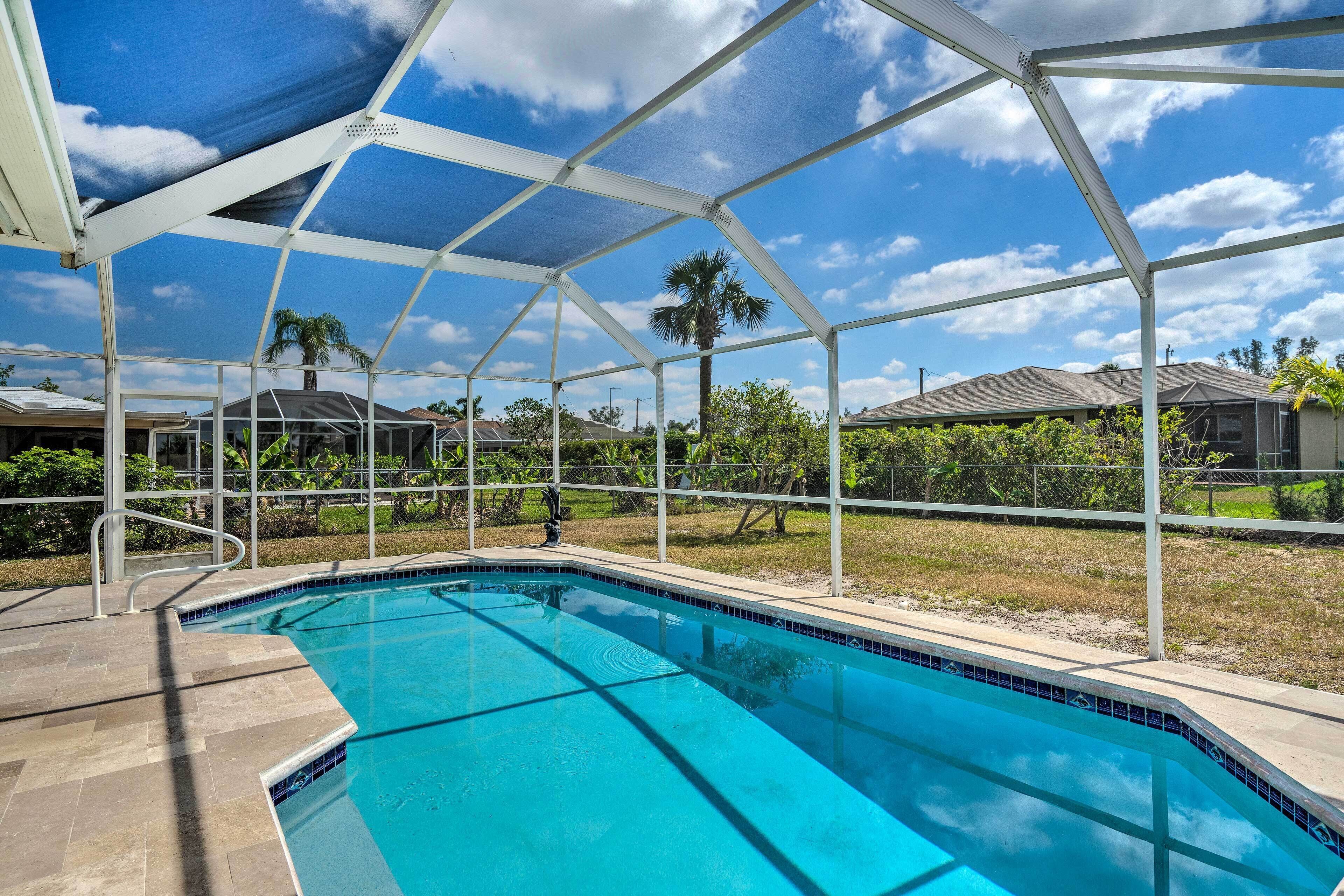Une piscine à l’eau d’un bleu limpide, entourée d’un espace abrité doté d’un toit et offrant une vue sur les maisons au loin.