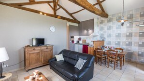 Un salon avec un canapé en cuir noir, un meuble en bois et un coin repas comprenant une table et des chaises.