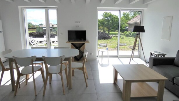 Un salon moderne comprenant un coin repas, de grandes fenêtres et un téléviseur.