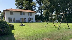 Une maison avec un toit recouvert de tuiles rouges, une cour gazonnée et une balançoire.