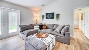 Ein modernes Wohnzimmer mit einem grauen Ecksofa, einem Holztisch und einer Karo-Decke.