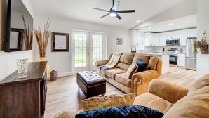 A spacious living room with a large sofa, a coffee table, and a TV mounted on the wall. There is a kitchen area with modern appliances and cabinets. - 1 Mi to Links! Resort Home Near Raceway in Sebring (Sebring)