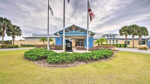 A building with a blue roof and white walls, surrounded by well-maintained grass and palm trees. - 1 Mi to Links! Resort Home Near Raceway in Sebring (Sebring)