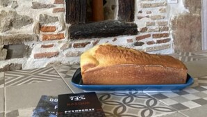 Un muro de piedra con una ventana de madera rústica, un pan sobre una bandeja azul y un libro titulado "DO MASQUE".