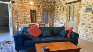 Una sala acogedora con pared de piedra, un sofá azul oscuro y una mesa de centro de madera.