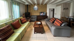 Un salon comprenant un canapé, un divan gris, une table basse en bois, un téléviseur et une cheminée.