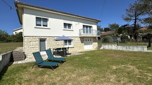 Een huis met twee verdiepingen, een gevel van steen, een balkon en een klein terras met een tafel en stoelen.