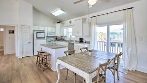 Una cocina amplia con armarios blancos, una mesa de comedor de madera y un ventilador de techo.