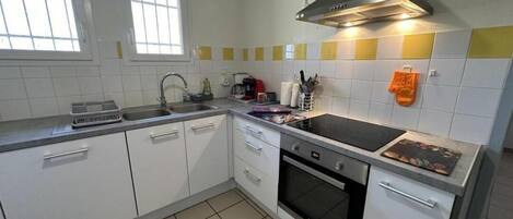 A kitchen with white cabinets, a stove, oven, and a sink.