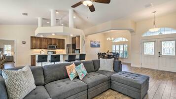 A spacious living room with a sectional sofa, a dining area, and a kitchen in the background.