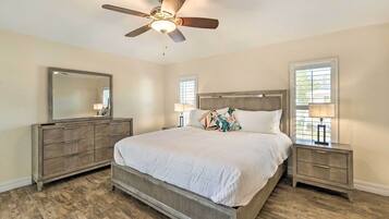 A bedroom with a bed, nightstands, a dresser, a ceiling fan, and a large mirror.