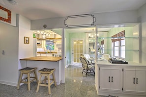 A kitchen with a wooden island, two stools, a dining area with a chair, and a glass-fronted cabinet. - Vero Beach Oasis < 7 Mi to South Beach Park! (Vero Beach)